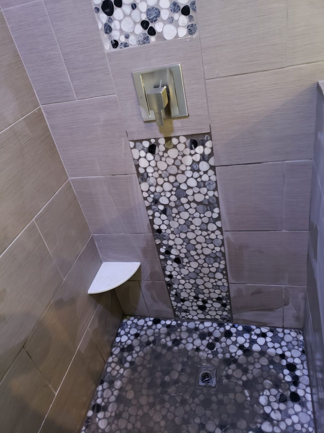 Shower with pebble mosaic floor and accent strip
